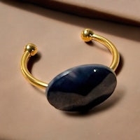 a gold plated cuff bracelet with a blue stone