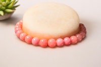 a pink beaded bracelet sitting on top of a plant